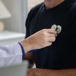 A nurse holding a stethoscope up to a man's chest